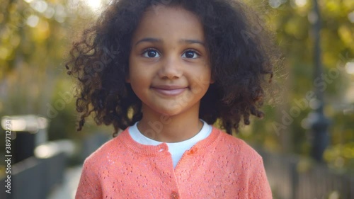 Close up of happy cute little african girl smiling at camera outdoors