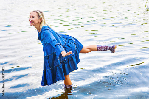 Photos blond woman in blue dress standing in water with rubber boots