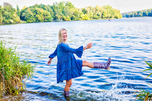 Foto blond woman in blue dress standing in water with rubber boots