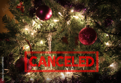 Red 'Canceled' text on a blurred decorated Christmas tree background with copyspace. Holiday season canceled concept due to Corona virus or other reasons. © Imladris