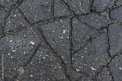 Dark texture of cracked asphalt, broken road surface.