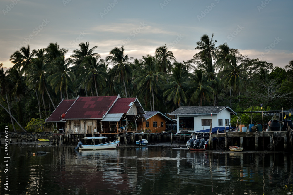 wooden houses at pier with palmtree background in evening time in thailand