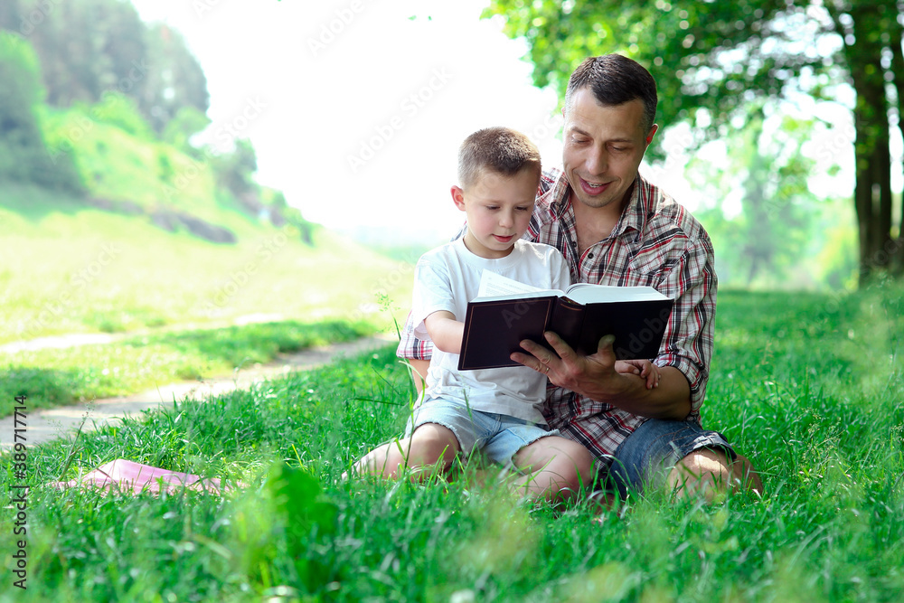 Father and son reading the Bible in nature Father and son reading the Bible in nature