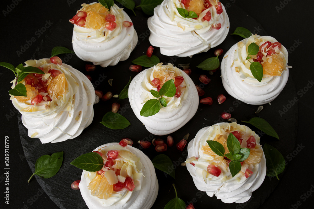 dessert called Anna Pavlova. Meringue with cream garnished with pomegranate, tangerine slices and Basil leaves dessert called Anna Pavlova. Meringue with cream garnished with pomegranate, tangerine slices and Basil leaves