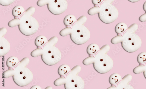 Christmas cookies pattern in the shape of a snowman decorated with icing sugar and fondant on a pink background