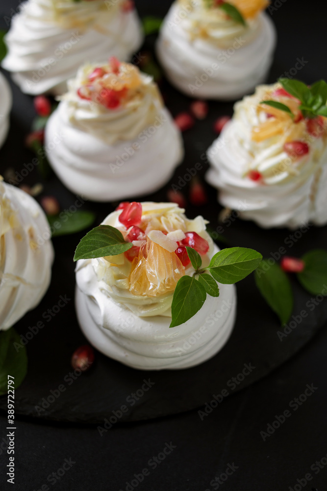 dessert called Anna Pavlova. Meringue with cream garnished with pomegranate, tangerine slices and Basil leaves dessert called Anna Pavlova. Meringue with cream garnished with pomegranate, tangerine slices and Basil leaves