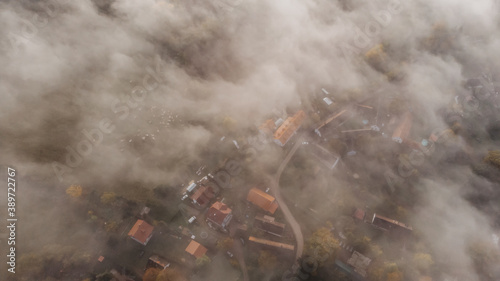 Aerial view of a small village in fog.Top view of traditional housing estate in Czech.Looking straight down with a satellite image style.Houses from above, real estate concept.Foggy landscape.