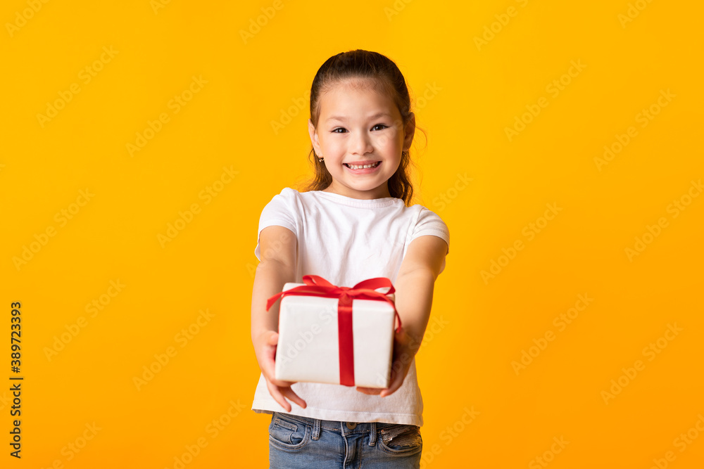 Happy asian girl giving you gift box at orange studio