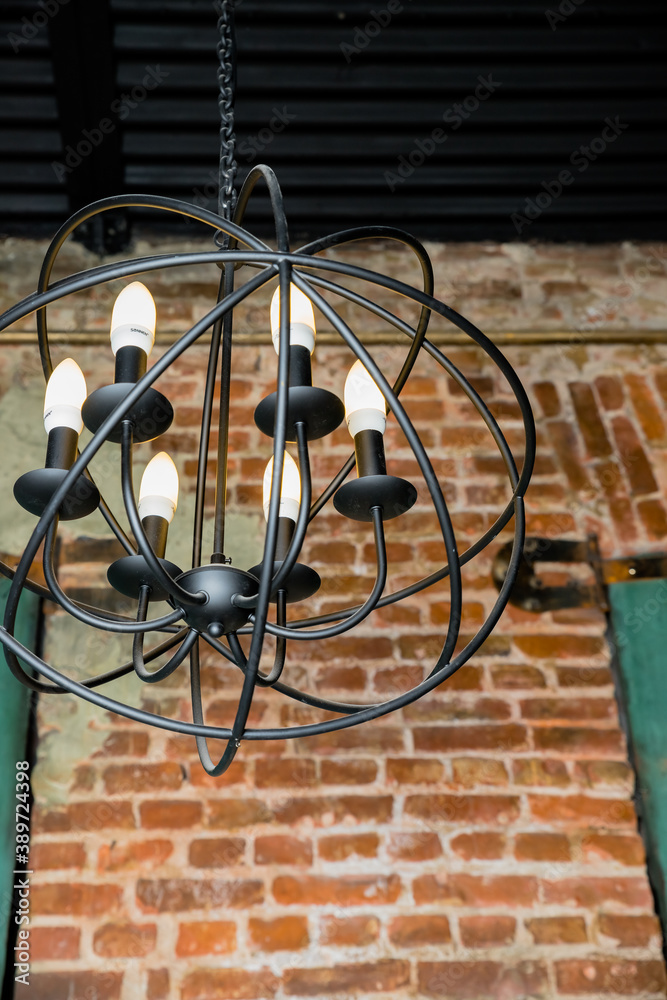 round chandelier, gold, brass, different shapes of a circles, inside lamp there are candles. Fashion design chandeliers.Old fashioned lantern.lamps hanging at restaurant over brick background