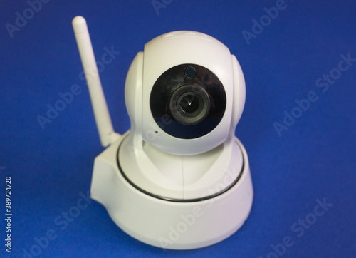 Wi-fi camera close-up on a bright blue background. Digital white video surveillance. Home security gadgets. Selective focus  shallow depth of field