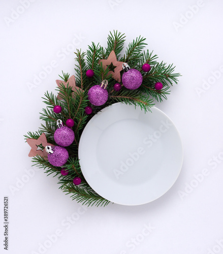 Creative concept holiday celebration photo of christmas toys balls decoration with plate dish food on white background.