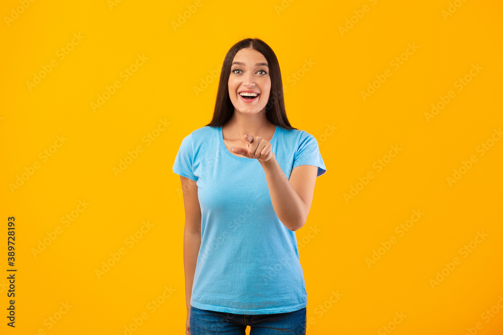 Happy female pointing finger at camera at studio Happy female pointing finger at camera at studio
