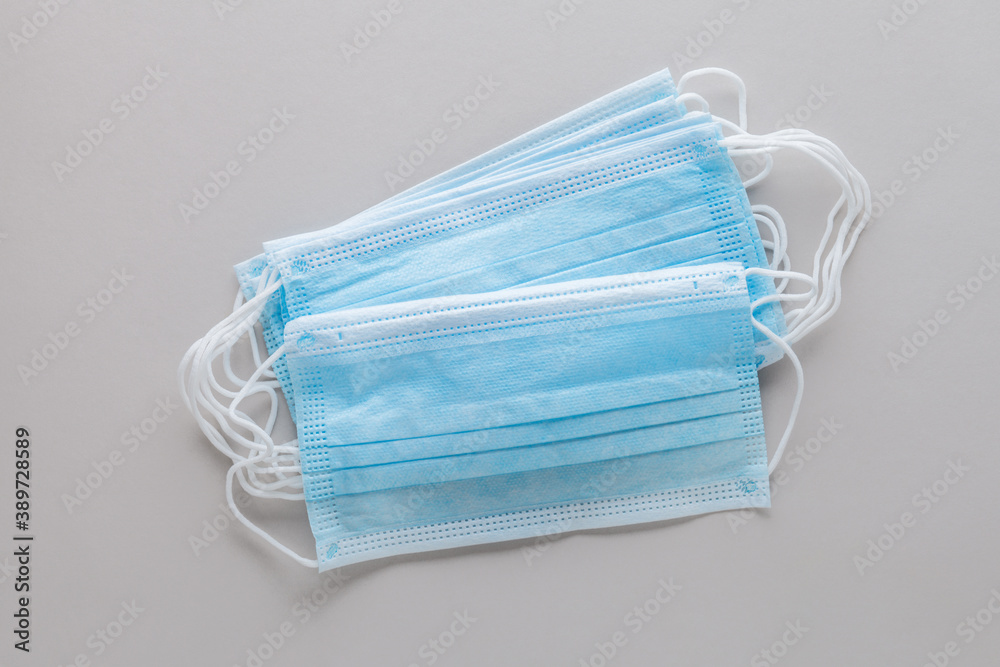 pair of blue medical surgical protective masks to cover nose and mouth isolated on gray background, top view, flat lay pair of blue medical surgical protective masks to cover nose and mouth isolated on gray background, top view, flat lay