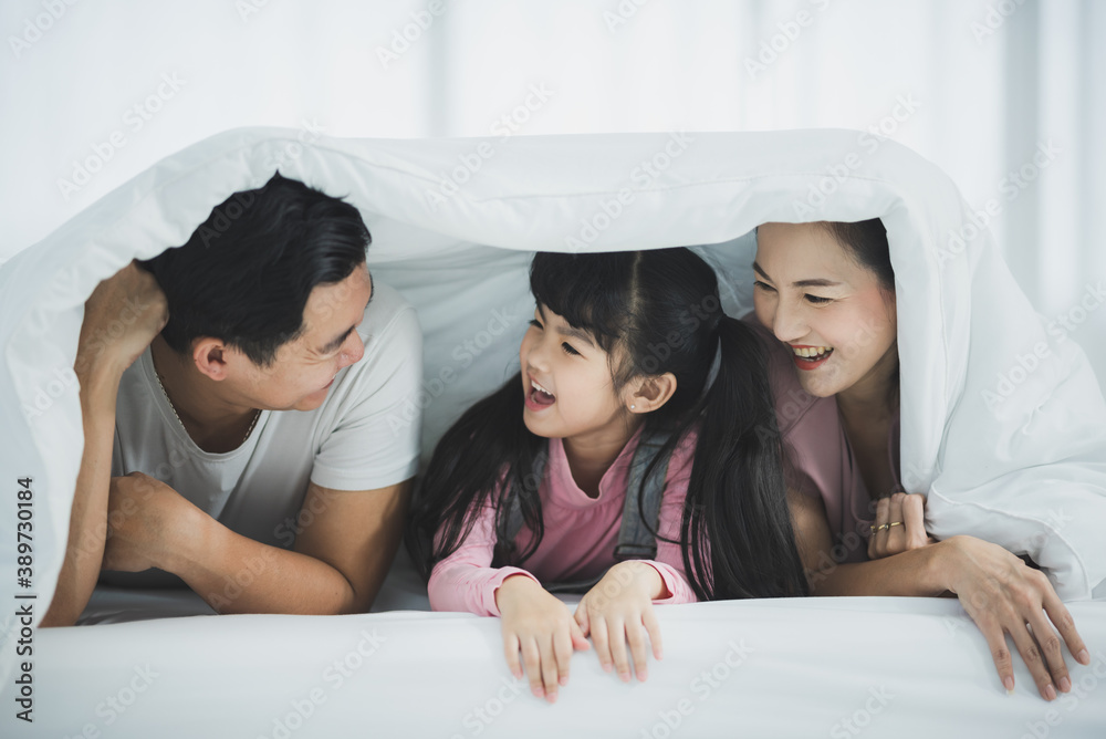 Happy Asian family laying on bed with smile Happy Asian family laying on bed with smile