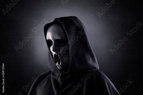 Ghostly figure in hooded cloak in the dark