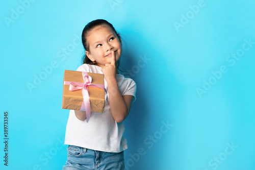 Happy girl holding gift box at blue studio © Prostock-studio