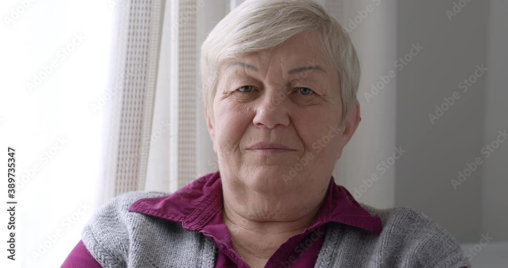 Portrait of an old, elderly woman looking at the camera. 4K.