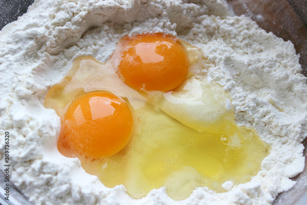 A bowl of flour and egg on the kitchen table.Preparation of home-made dough. Baking ingredients A bowl of flour and egg on the kitchen table.Preparation of home-made dough. Baking ingredients