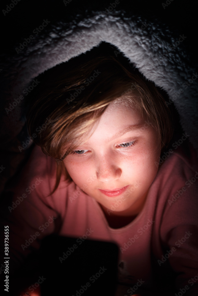 Girl under the covers on Internet from smartphone. Girl under the covers on Internet from smartphone.