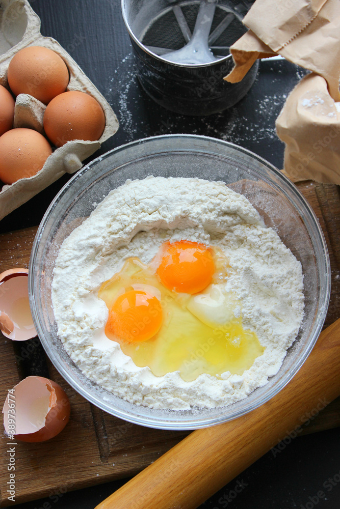 A bowl of flour and egg on the kitchen table.Preparation of home-made dough. Baking ingredients A bowl of flour and egg on the kitchen table.Preparation of home-made dough. Baking ingredients