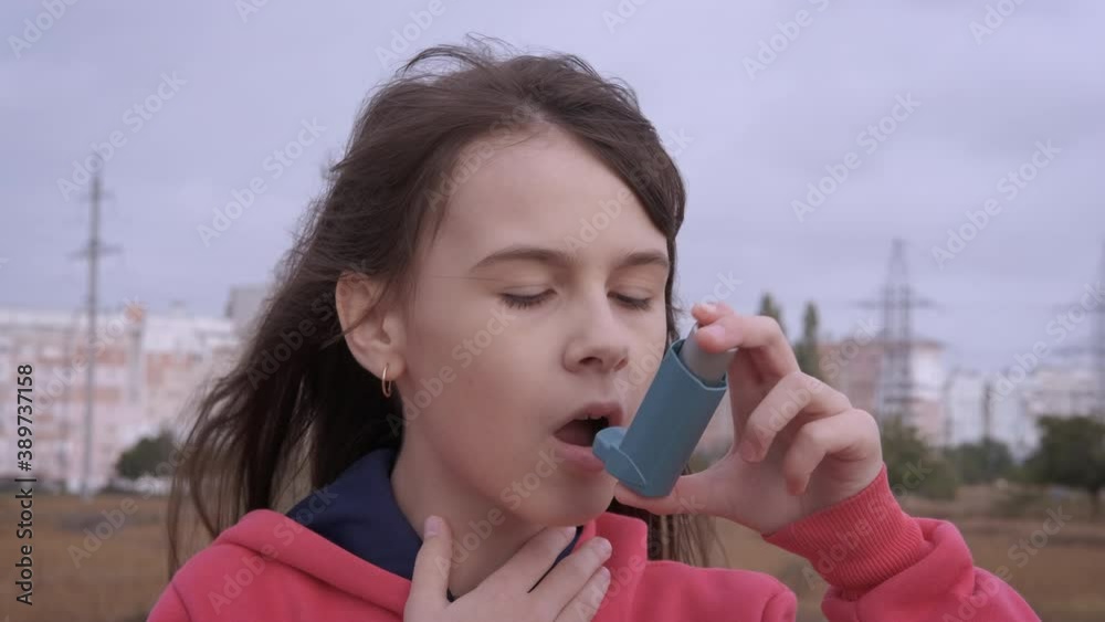 Suffering from asthma with inhaler. A teen with asthma attack use an inhaler with medication outside.