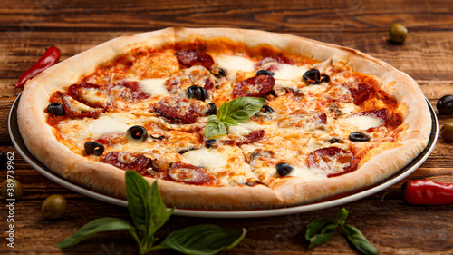 Pizza with meat and olives on a wooden background