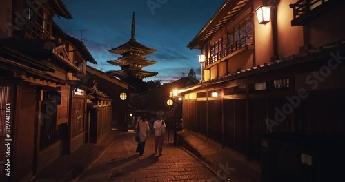 Kyoto, Japan with Kiyomizudera Temple in background, wide. People walk down dark alleyway