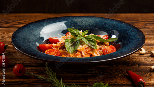 pasta with cherry tomatoes and basil on wooden background photo