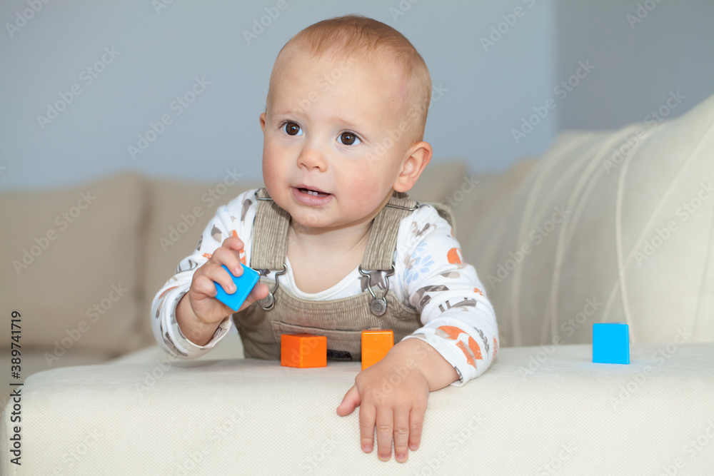 Adorable boy playing with toys. Adorable boy playing with plastic cube on sofa. Fine motor skills development concept. Adorable boy playing with toys. Adorable boy playing with plastic cube on sofa. Fine motor skills development concept.