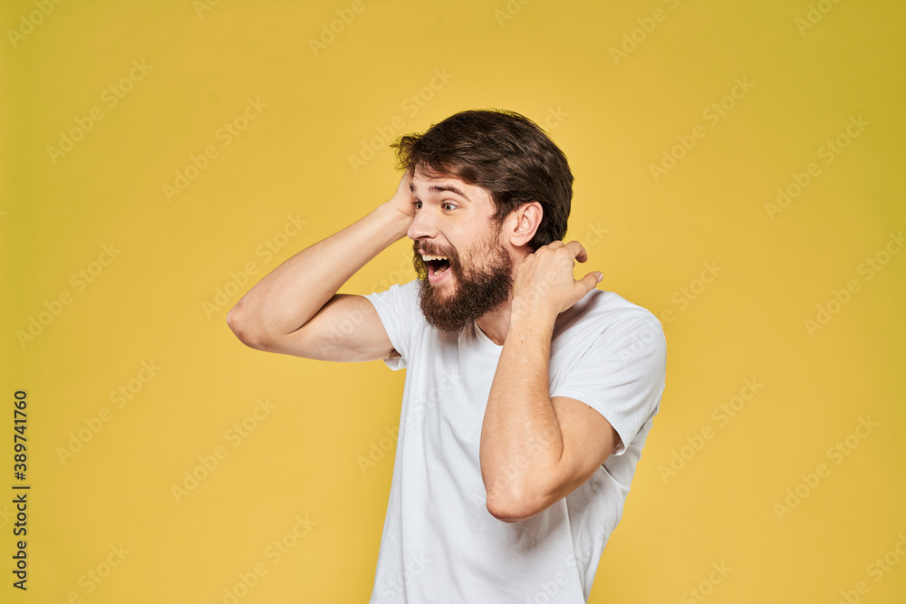 Man gesturing with hands emotions lifestyle white t-shirt yellow isolated background Man gesturing with hands emotions lifestyle white t-shirt yellow isolated background
