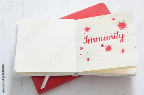 Notebook with word Immunity on white wooden table photo