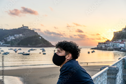 30-year-old man with a mask poses with the sea in the background