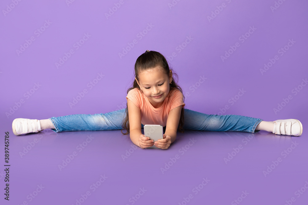 Cute little girl making splits and using smartphone Cute little girl making splits and using smartphone