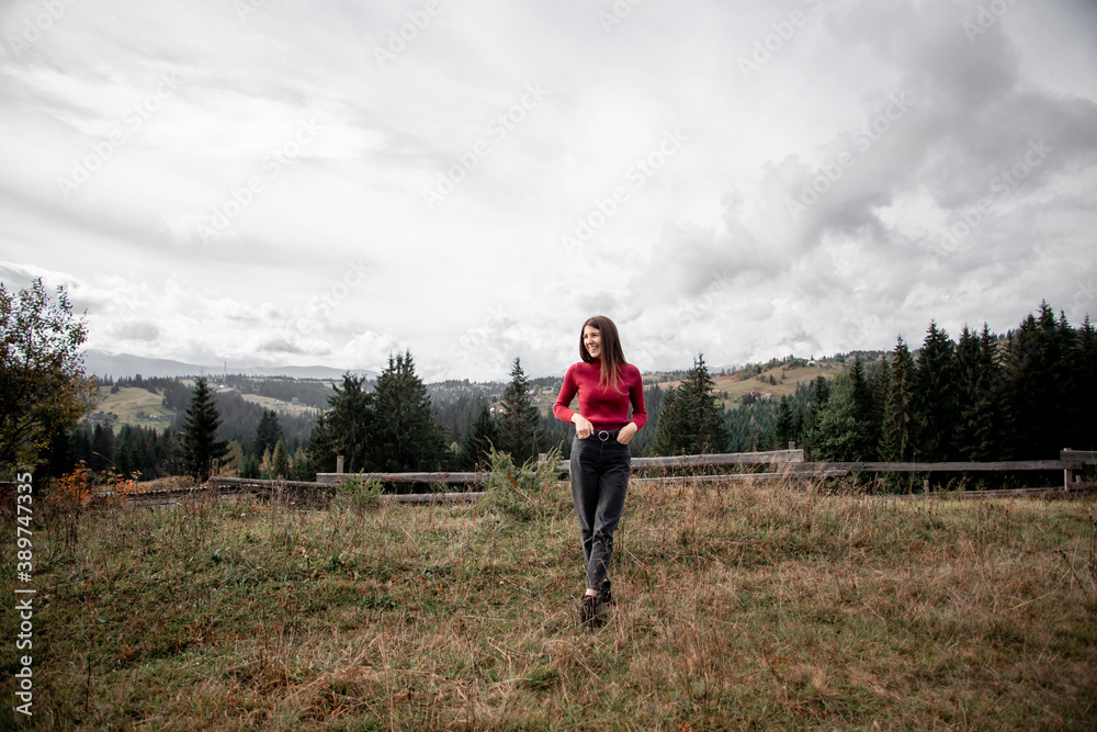 portrait of a young pretty girl who stands alone against a 
background of mountains. beautiful sky, beautiful nature