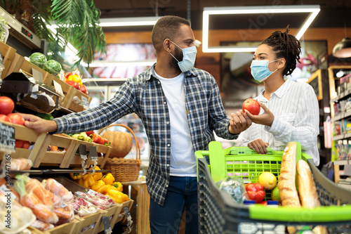 Couple In Masks Buying Vegetables Doing Grocery Shopping In Store