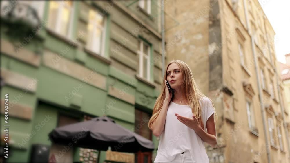 Slow motion front view of a Young beautiful blonde woman in stylish clothes walking and calling on phone in the street Slow motion front view of a Young beautiful blonde woman in stylish clothes walking and calling on phone in the street