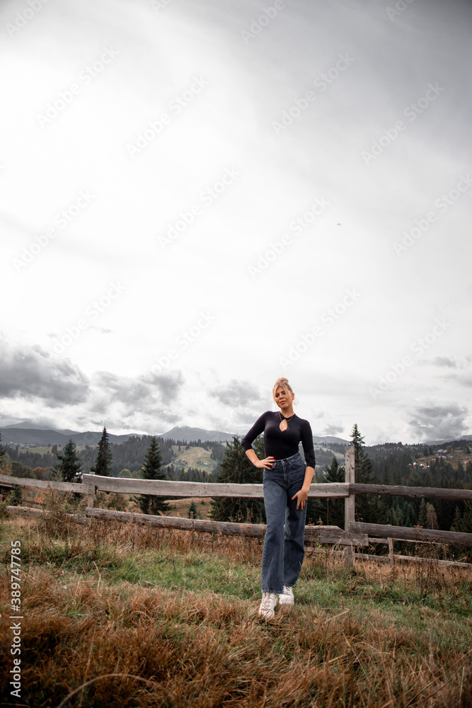 portrait of a young pretty girl who stands alone against a 
background of mountains. beautiful sky, beautiful nature