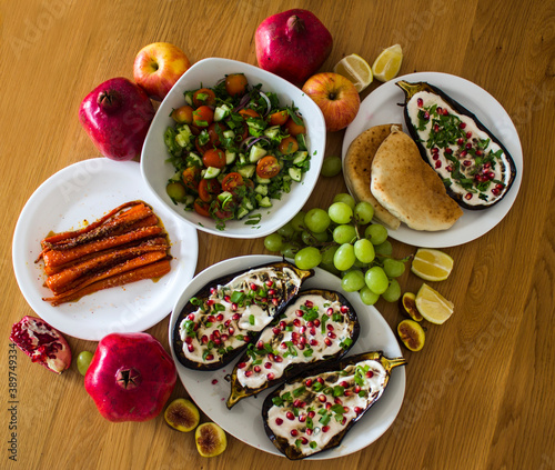 Grilled eggplants, salad, caramelized carrots and fresh fruits on wooden table. Top view photo of different vegetarian meals. 