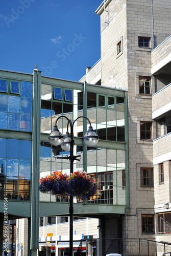 Modern Multi Storey Car Park with Reflective Glass Footbridge & Foreground Hanging baskets