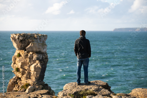 Caucasian man in sea cliffs landscape in Cabo Carvoeiro Cape looking at Berlengas Island, in Peniche, Portugal