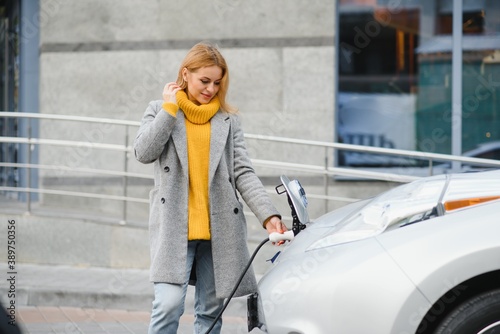 Woman charging electro car at the electric gas station