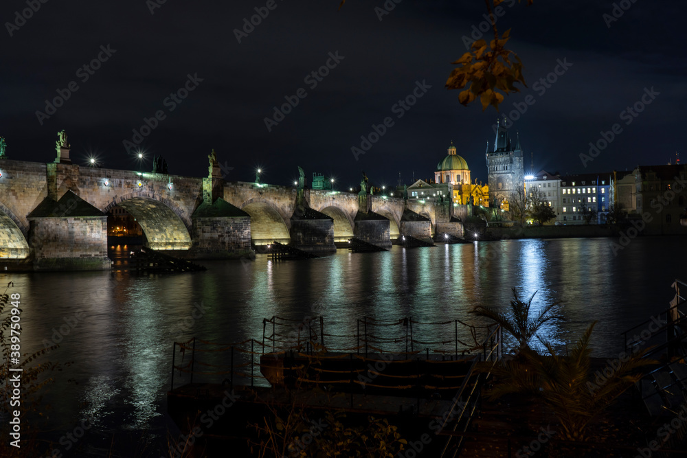 
illuminated stone monument of karluv bridge from 14 century on river vltava and light from street lighting in the center of prague and prague architecture around
