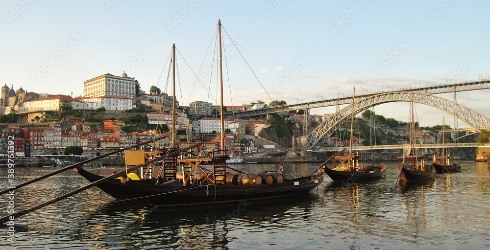 Barcos rabelos parados, ancorados no rio d'ouro no Porto com vista para a baixa da cidade e com a ponte D. Luís de fundo - Engenheiro Eiffel - Transporte de vinhos