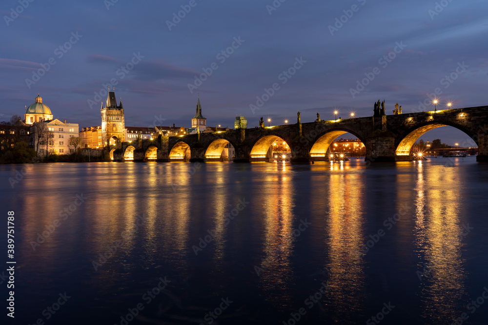 
illuminated stone monument of Charles Bridge from the 14th century on the Vltava river and lights from street lighting in the center of Prague