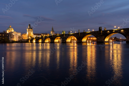  illuminated stone monument of Charles Bridge from the 14th century on the Vltava river and lights from street lighting in the center of Prague
