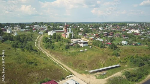 Aerial view of a village in ecological area with many houses and a church. Clip. Rural empty road leading to the village on blue cloudy sky background. photo