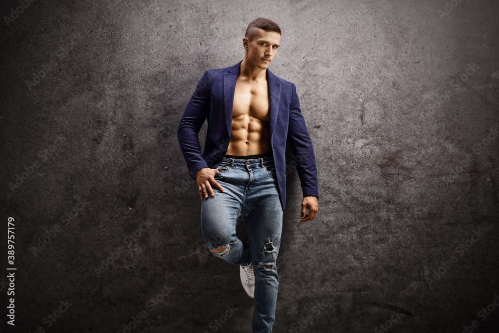 Handsome male with suit, shirtless, leaning on a rusty gray wall Handsome male with suit, shirtless, leaning on a rusty gray wall