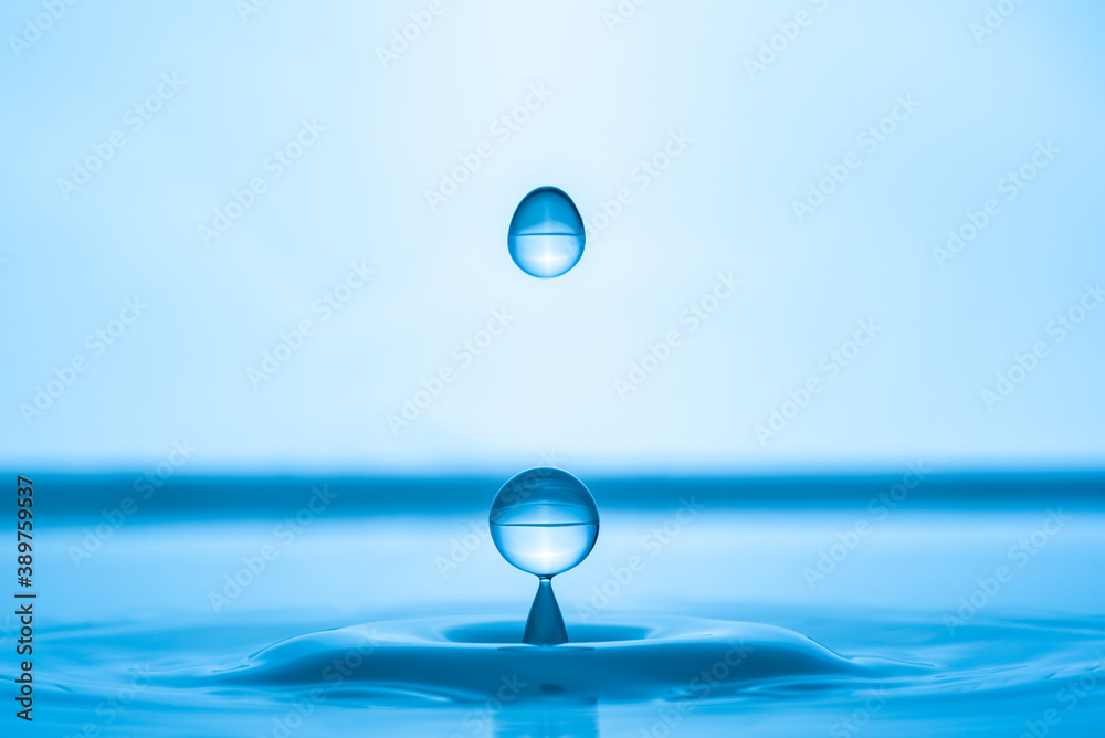 Water drop splashing into blue water surface Water drop splashing into blue water surface
