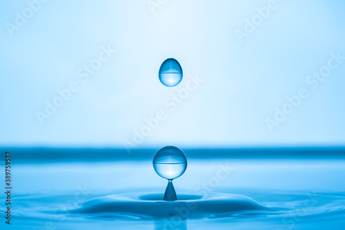 Water drop splashing into blue water surface
