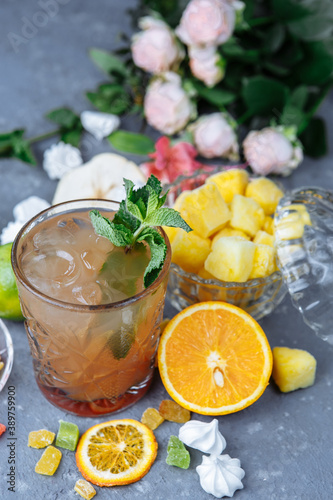 Cold refreshing pineapple cocktail with lime and mint for a hot summer day on a gray background decorated with candied fruit, mint and pineapple cubes. mojito idea, homemade lemonade with ice cubes